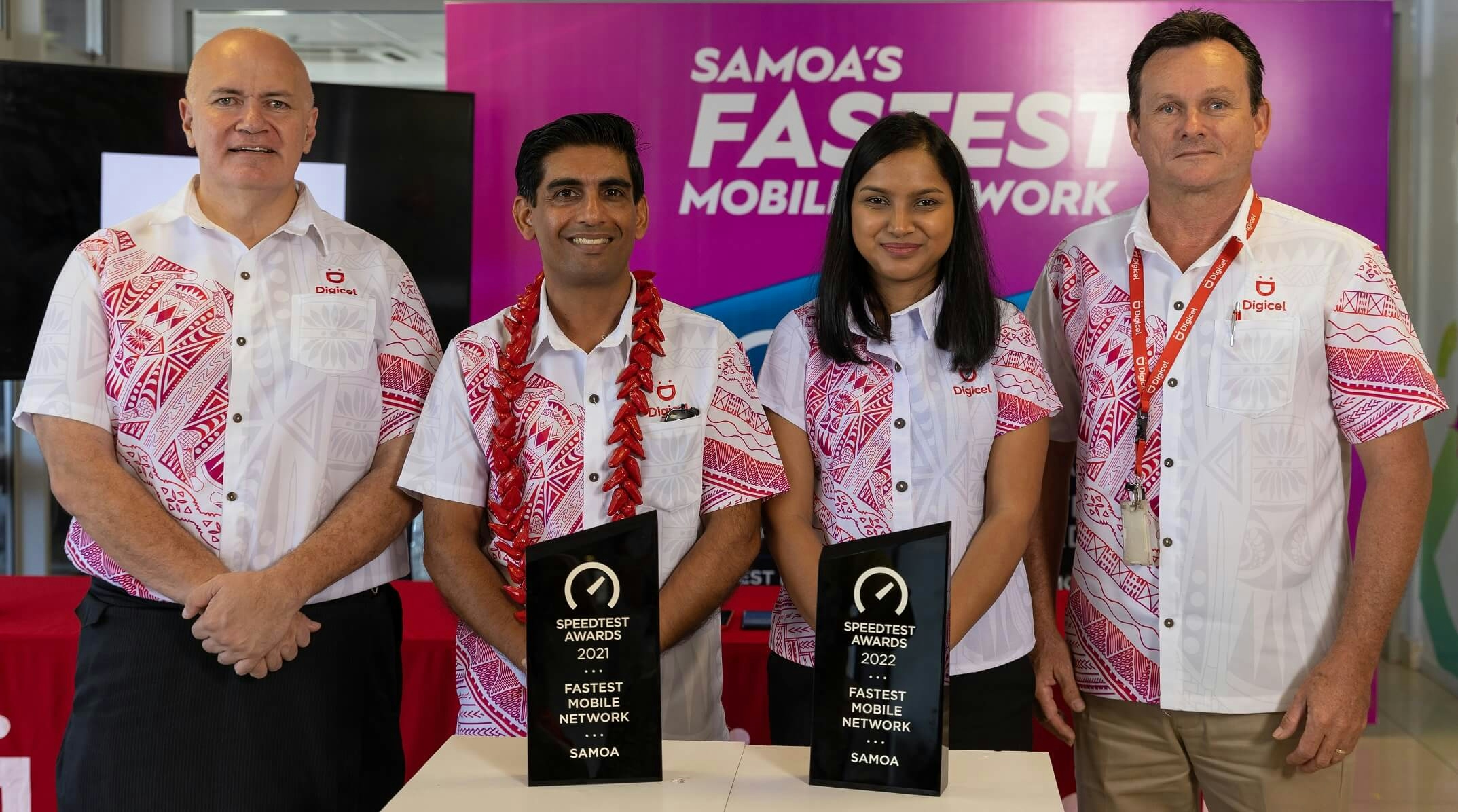 Four Digicel employees standing with the 2021 and 2022 Fastest Mobile Network awards