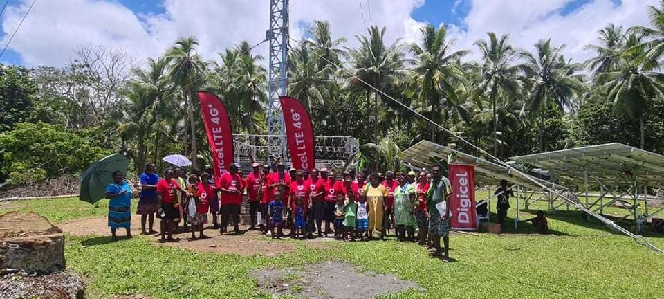 A group of Digicel staff standing in front of the new cell tower at Big Bay